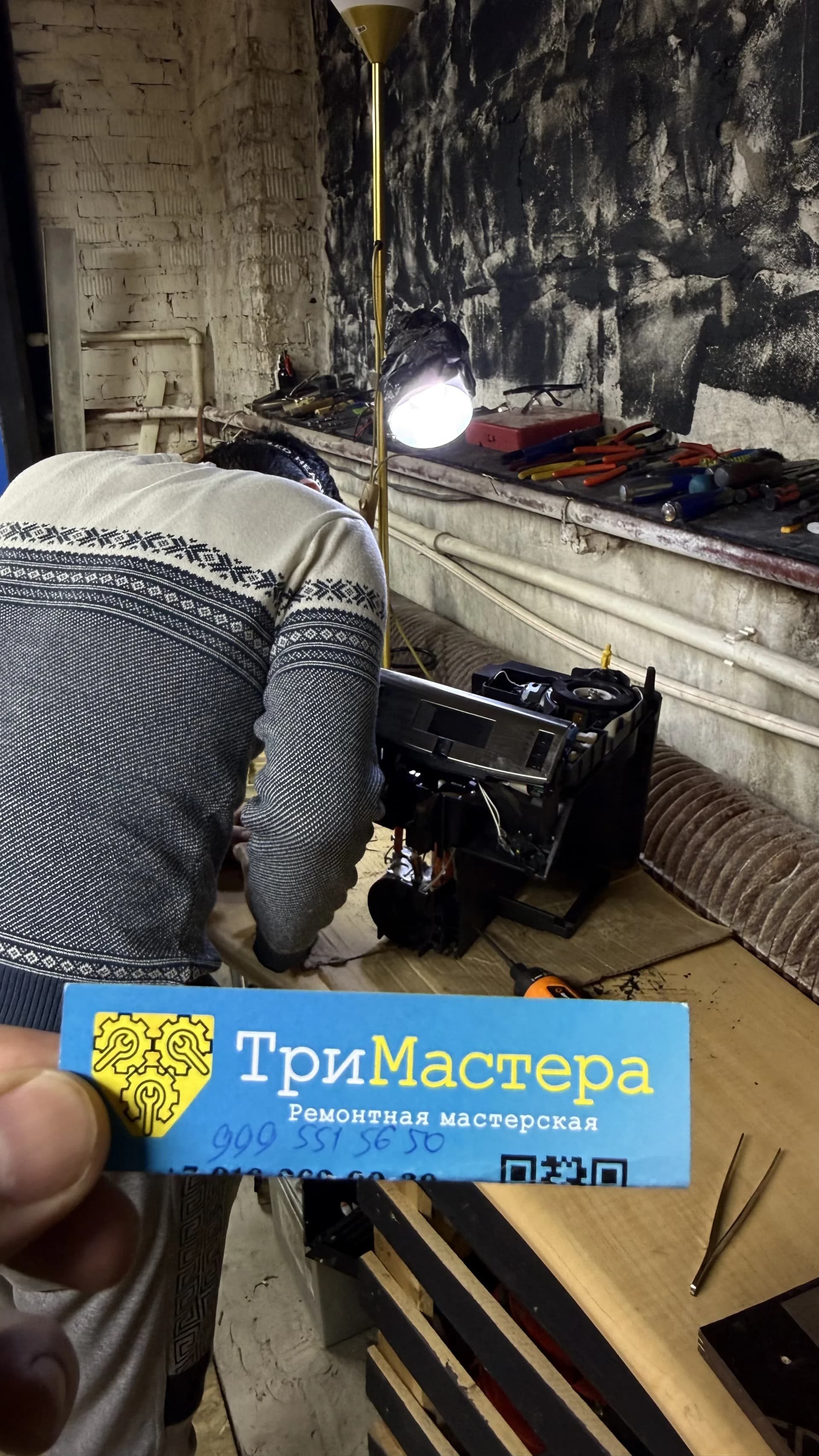 Специалист ремонтирует автоматическую кофемашину в мастерской «ТриМастера»